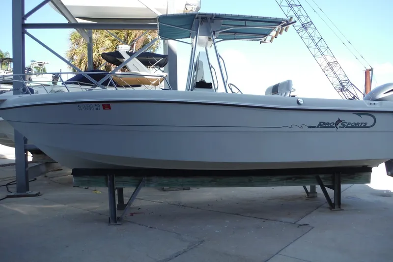 Slide: The Image of 1999 Pro Sports 2200 CC boat on dry dock, featuring a sleek design and canopy. - 2