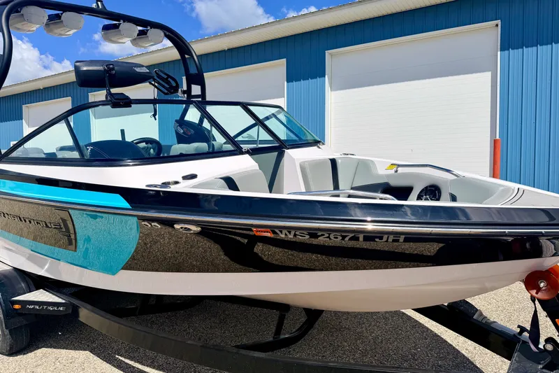 Slide: The Image of 2014 Nautique Super Air Nautique 210 boat parked near blue building. - 13