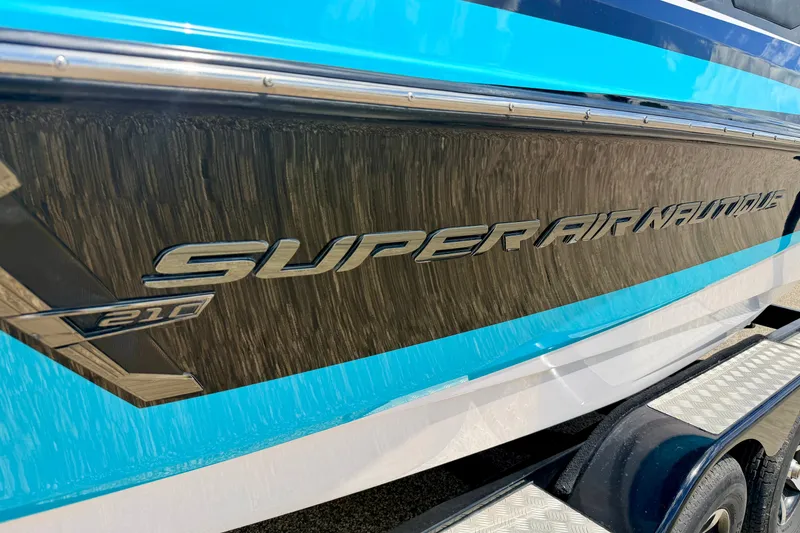 Slide: The Image of 2014 Nautique Super Air Nautique 210 boat side view with logo detail. - 8