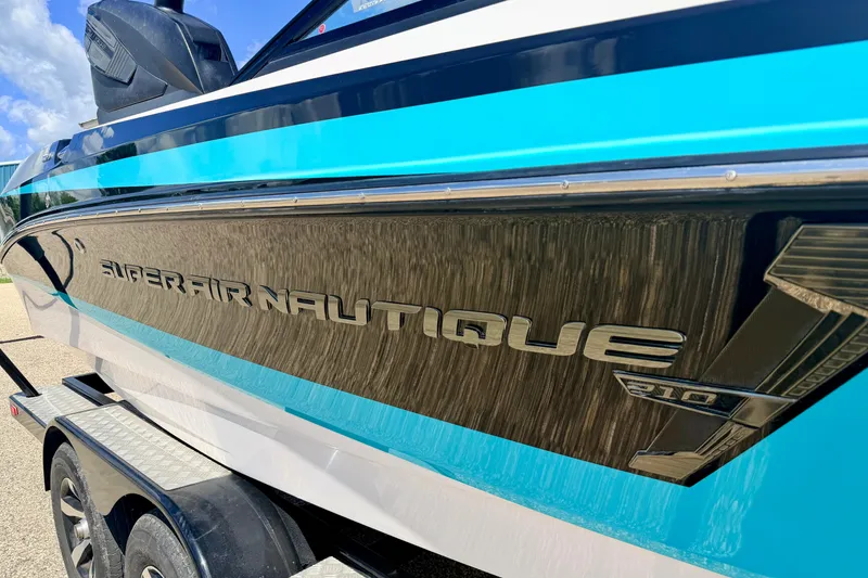 Slide: The Image of 2014 Nautique Super Air Nautique 210 boat with blue and black detailing on trailer. - 12