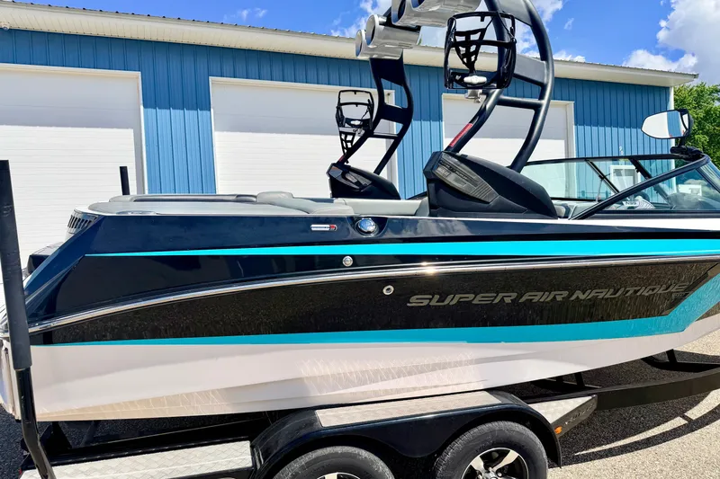 Slide: The Image of 2014 Nautique Super Air Nautique 210 boat on trailer, blue and white exterior. - 14