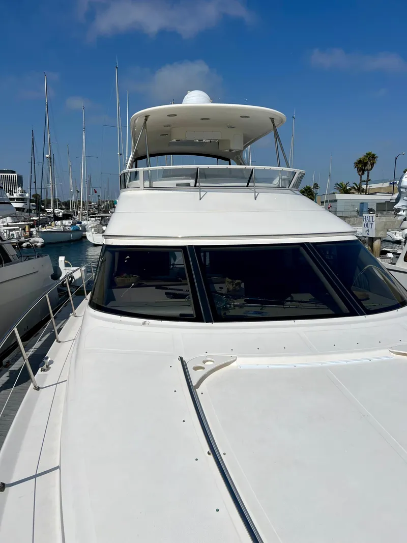 Slide: The Image of 2002 Sea Ray 560 Sedan Bridge yacht docked in a marina under a clear blue sky. - 14