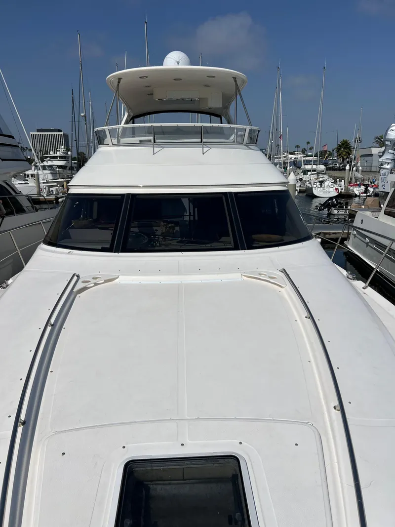 Slide: The Image of 2002 Sea Ray 560 Sedan Bridge yacht docked in a marina under clear blue skies. - 15