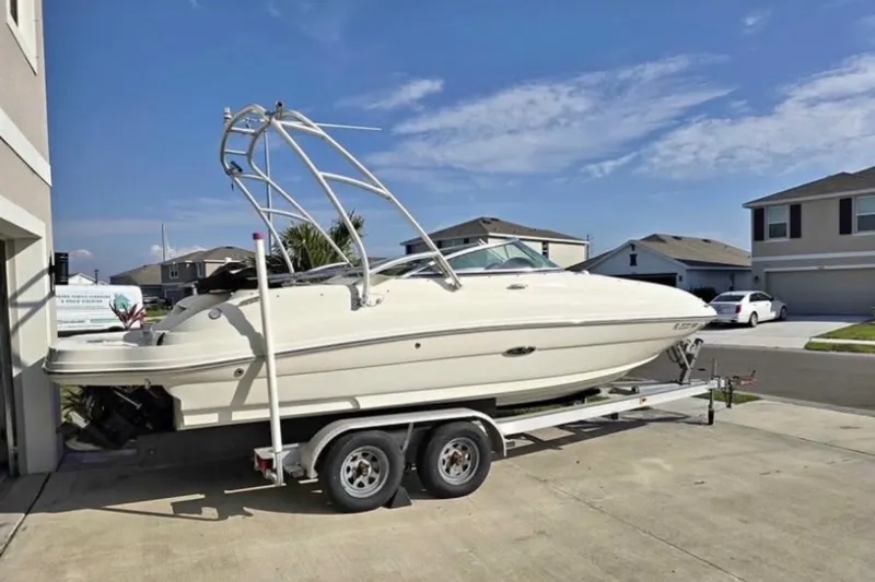 Slide: The Image of 2006 Sea Ray 220 Sundeck boat on trailer in suburban driveway under clear sky. - 14