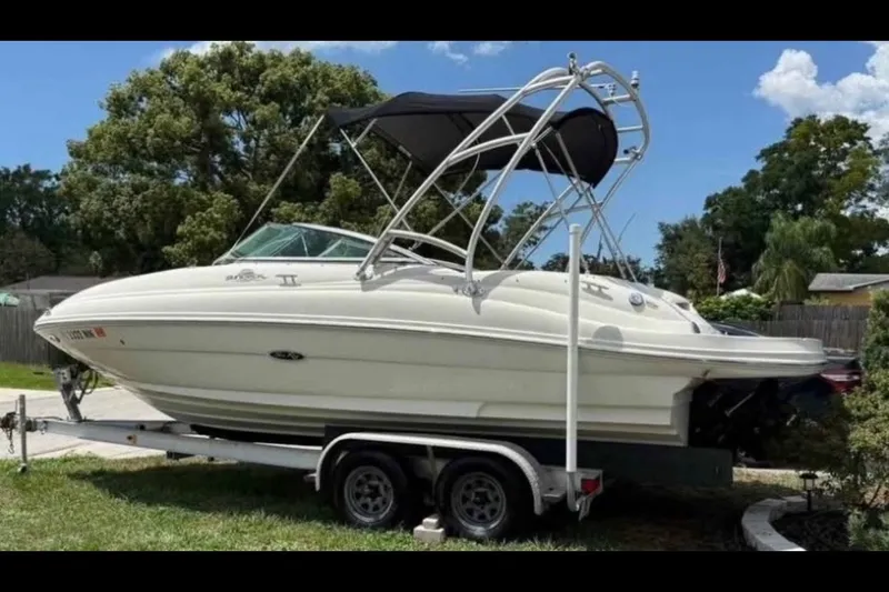 Slide: The Image of 2006 Sea Ray 220 Sundeck boat on trailer, parked outdoors under clear sky. - 1