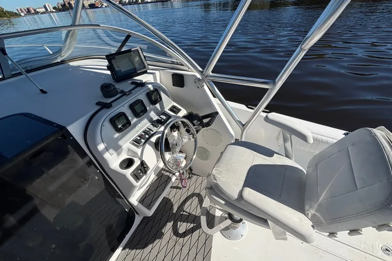 Slide: The Image of 2008 Angler 220WA boat cockpit with steering wheel, controls, and seating by the water. - 12