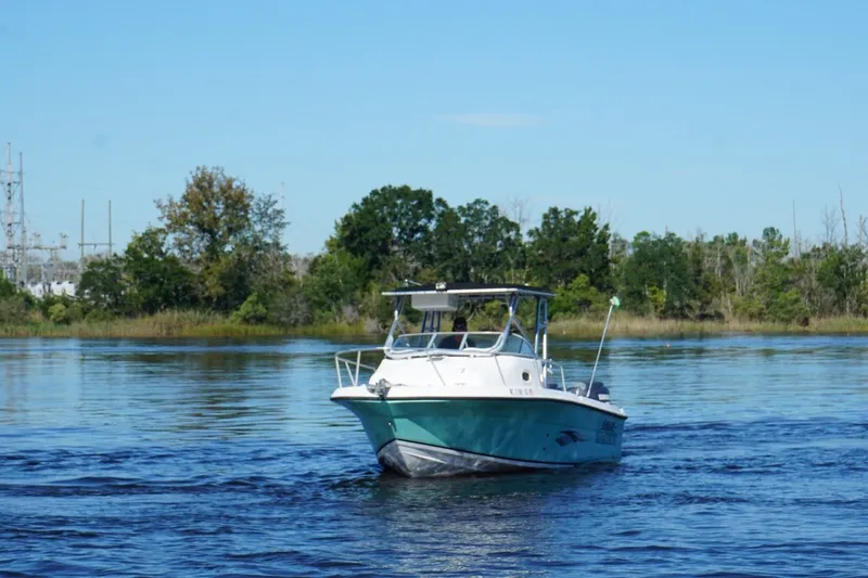 Slide: The Image of 2008 Angler 220WA boat cruising on a calm lake with trees in the background. - 4