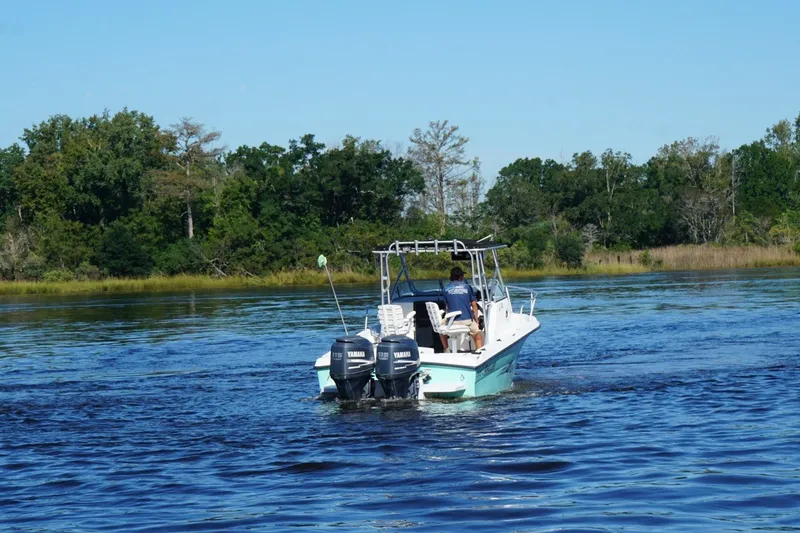 Slide: The Image of 2008 Angler 220WA boat cruising on a scenic river with lush green trees. - 1