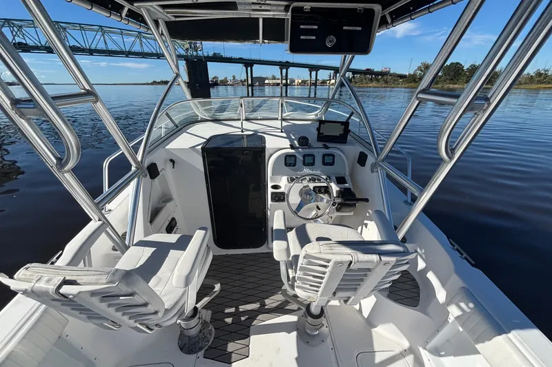 Slide: The Image of 2008 Angler 220WA boat interior with steering wheel and seating on calm water. - 13