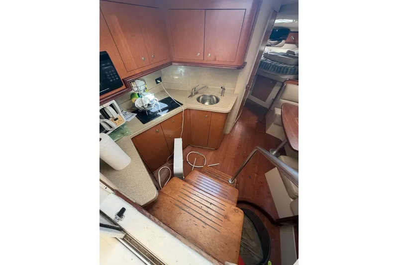 Slide: The Image of 2004 Cruisers Yachts 340 Express interior with kitchenette and wooden cabinetry. - 13