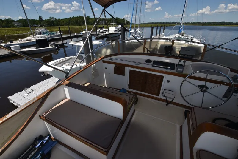 Slide: The Image of 1985 Albin 43 Trawler interior with steering wheel, docked at marina under blue sky. - 9
