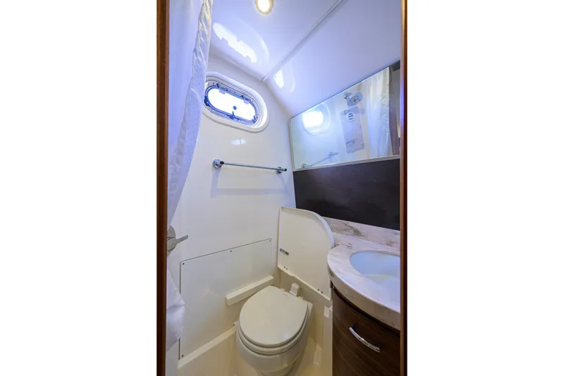 Slide: The Image of 2020 Pursuit S 368 Sport boat bathroom with toilet, sink, and porthole window. - 37