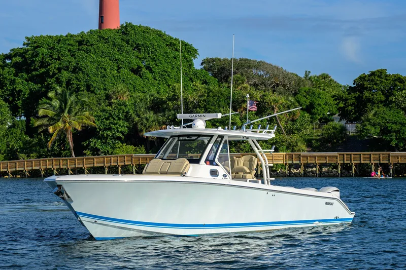 Slide: The Image of 2020 Pursuit S 368 Sport boat cruising near lush green shoreline and wooden dock. - 40