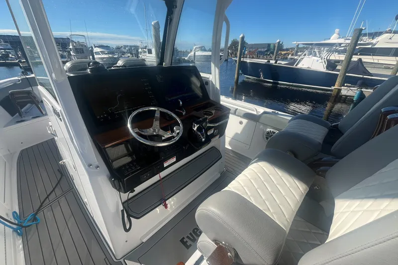 Slide: The Image of 2025 Everglades 315 Center Console boat interior with steering wheel and seating at marina. - 6