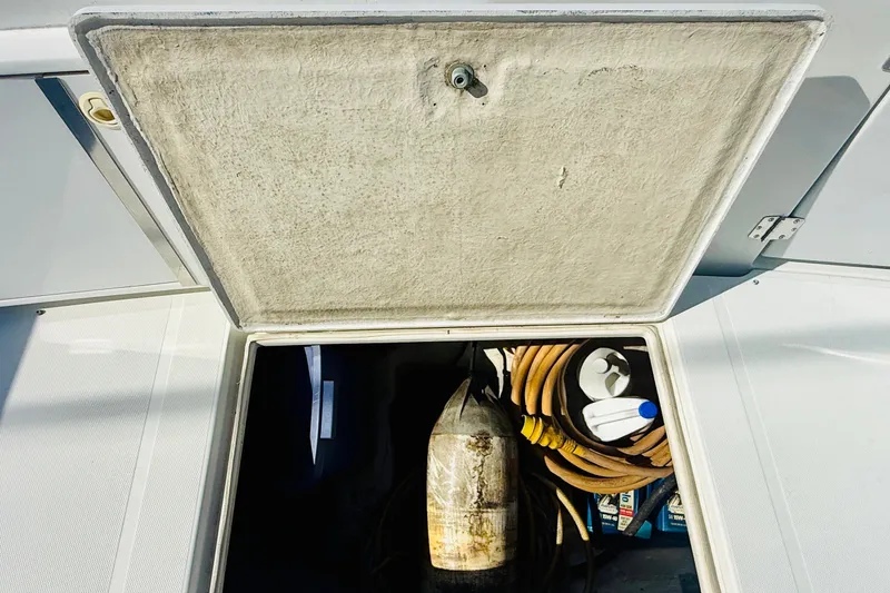 Slide: The Image of Open storage compartment on 2001 Carver 444 Cockpit Motor Yacht with hoses and cleaning supplies. - 19