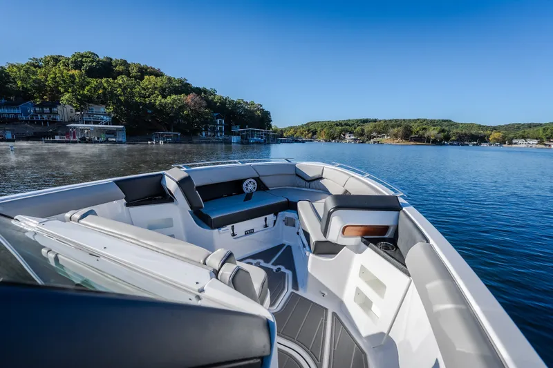 Slide: The Image of 2026 Monterey Elite 30 OB boat on a serene lake with lush green shoreline. - 45