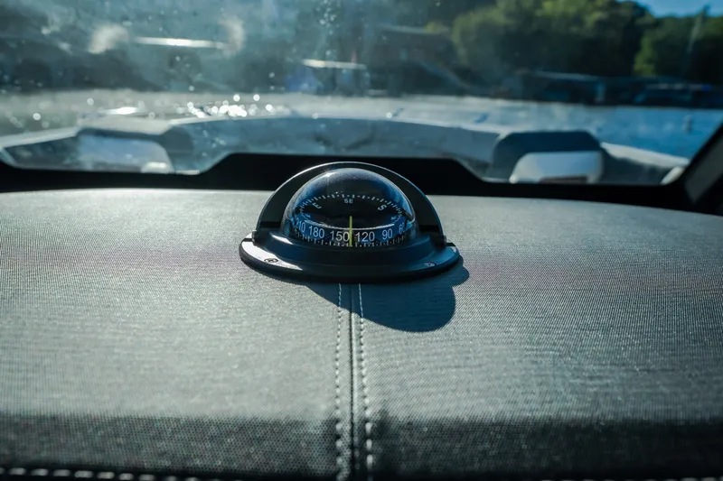 Slide: The Image of Compass on dashboard of 2026 Monterey Elite 30 OB boat, with blurred water view. - 22