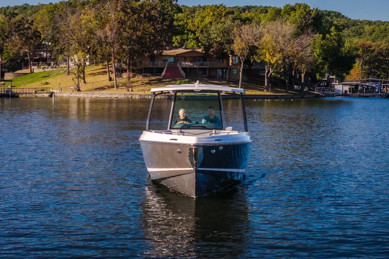 Slide: The Image of 2026 Monterey Elite 30 OB boat cruising on a serene lake near a wooded shoreline. - 73