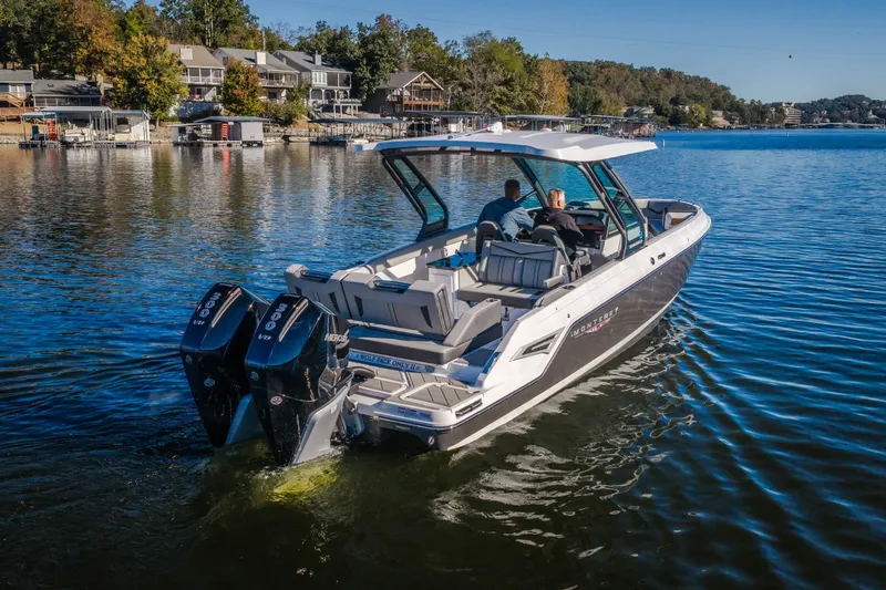 Slide: The Image of 2026 Monterey Elite 30 OB boat cruising on a serene lake near waterfront homes. - 68