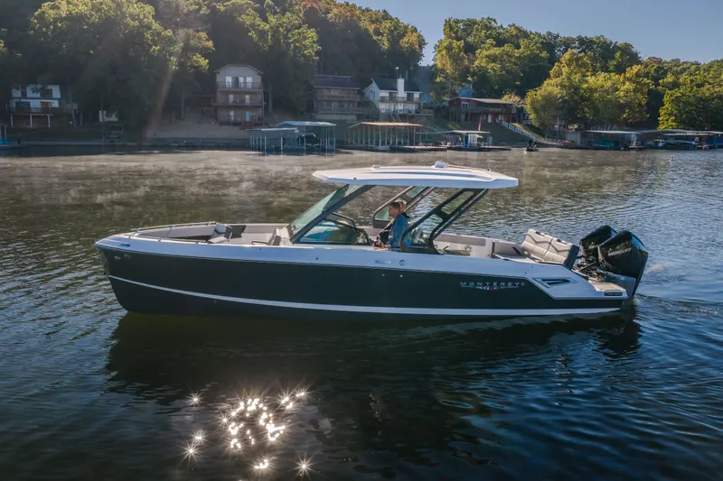 Slide: The Image of 2026 Monterey Elite 30 OB boat cruising on a serene lake with wooded shoreline. - 70