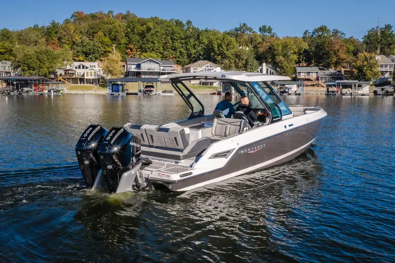 Slide: The Image of 2026 Monterey Elite 30 OB boat cruising on a scenic lake with waterfront homes. - 66