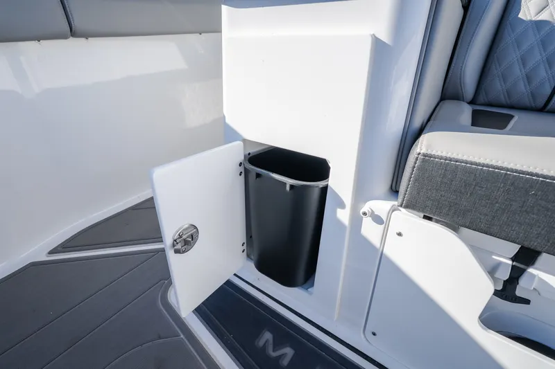 Slide: The Image of Interior of 2026 Monterey Elite 30 OB boat showing storage compartment with trash bin. - 40