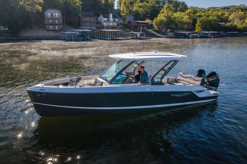Slide: The Image of 2026 Monterey Elite 30 OB boat cruising on a serene lake near a wooded shoreline. - 5