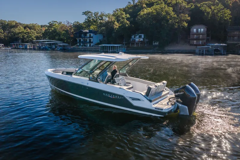 Slide: The Image of 2026 Monterey Elite 30 OB boat cruising on a serene lake near wooded shoreline. - 69