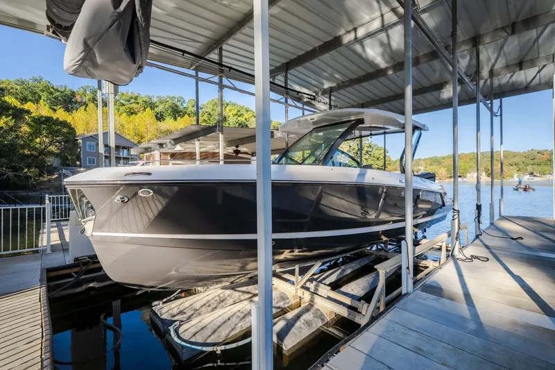 Slide: The Image of 2026 Monterey Elite 30 OB boat docked under a covered marina. - 77