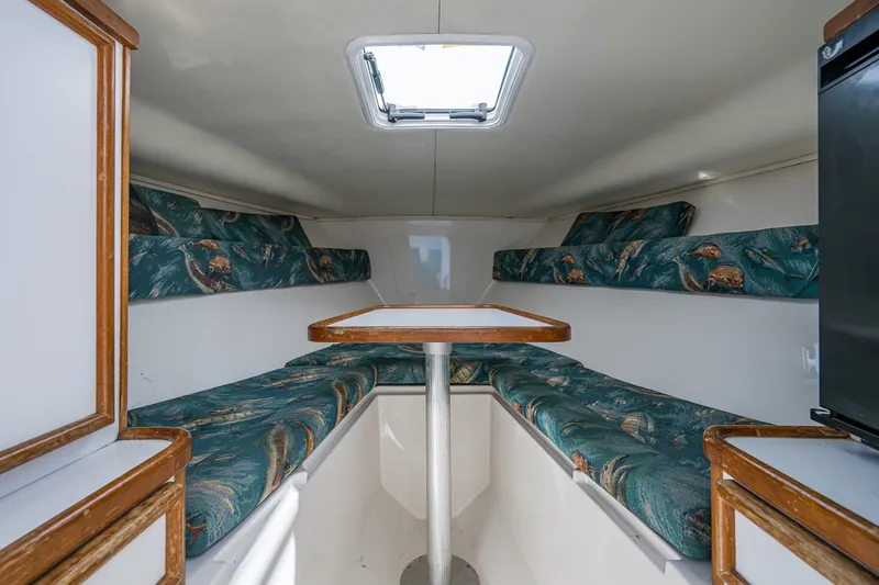 Slide: The Image of 2004 Jupiter 31 Cuddy cabin interior with seating and table, featuring patterned cushions. - 6