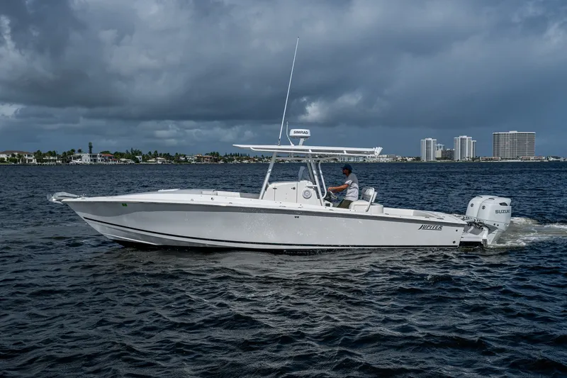 Slide: The Image of 2004 Jupiter 31 Cuddy boat cruising on water with city skyline in background. - 2