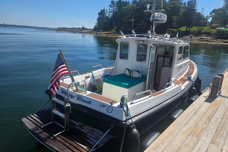 Slide: The Image of Mitchell Sea Angler 2002 boat docked, displaying American flag, calm waters, and scenic background. - 3