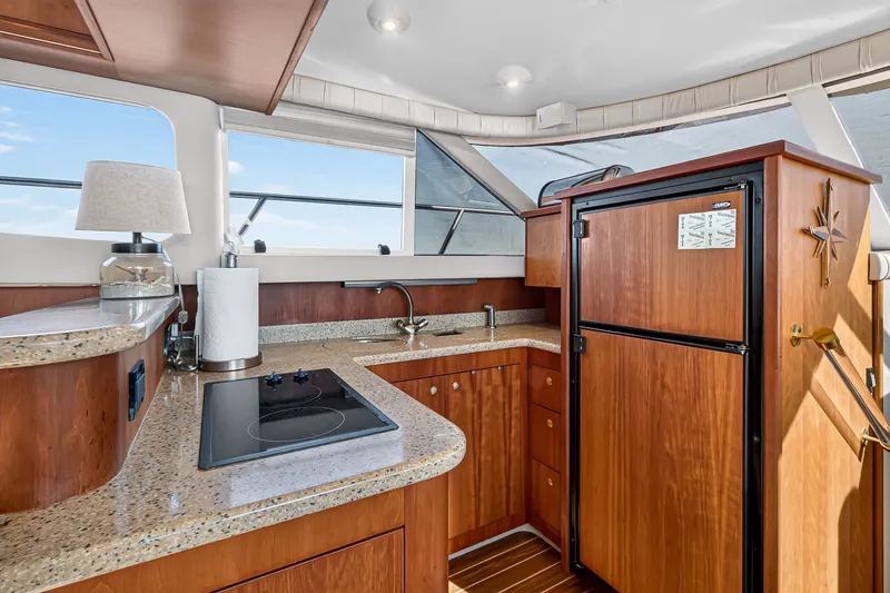 Slide: The Image of Luxurious 2003 Cruisers Yachts 4450 Express Motoryacht kitchen with wood cabinetry and modern appliances. - 38