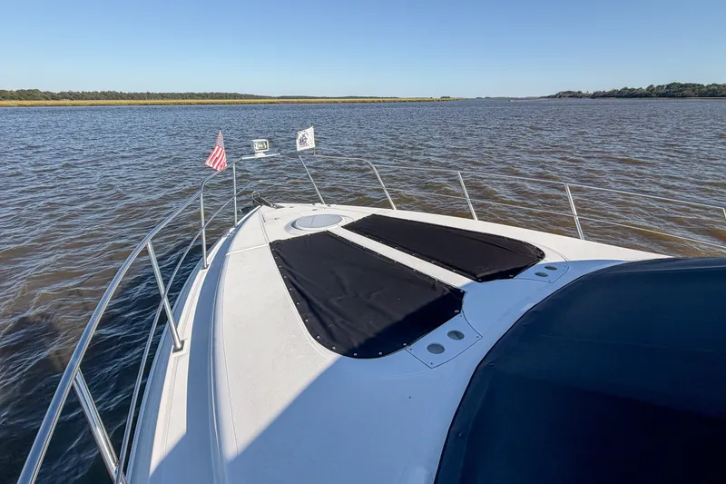 Slide: The Image of 2003 Cruisers Yachts 4450 Express Motoryacht on calm water, featuring deck and flags. - 24