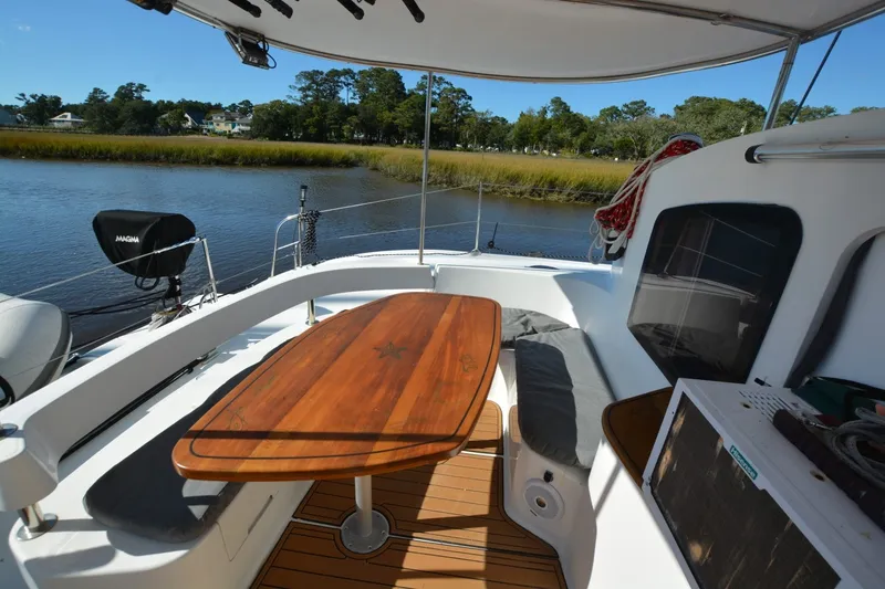 Slide: The Image of 2006 Fountaine Pajot LAVEZZI 40 catamaran cockpit with wooden table and scenic river view. - 16