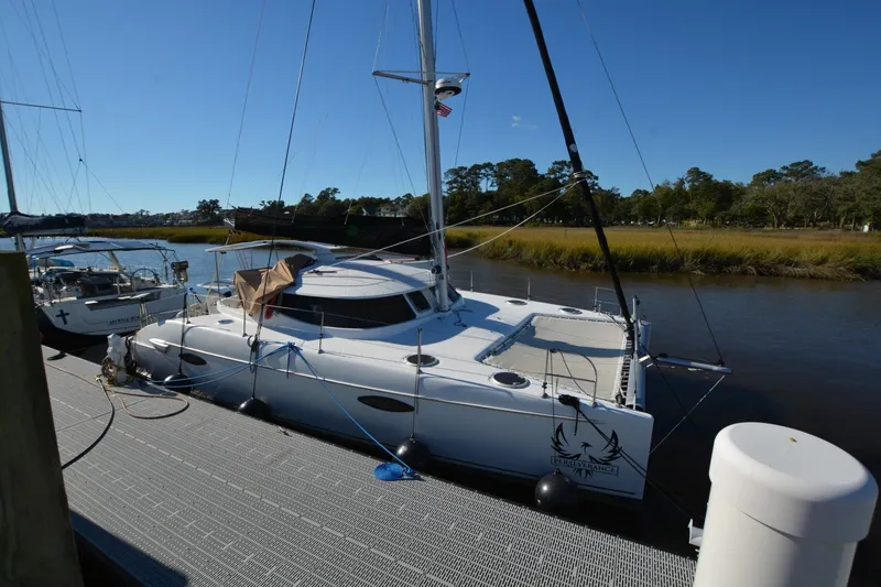 Slide: The Image of 2006 Fountaine Pajot LAVEZZI 40 catamaran docked by a serene riverbank. - 2