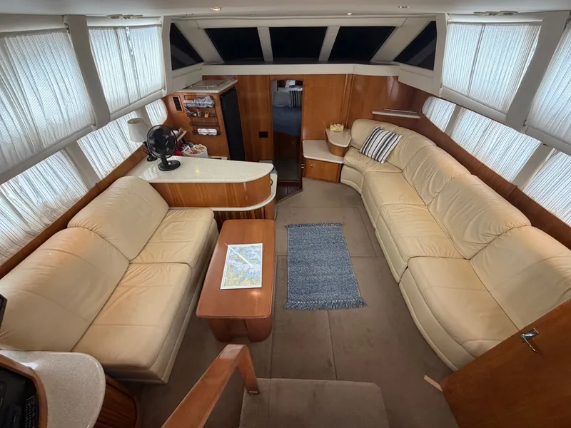 Slide: The Image of Interior of the 2002 Carver 396 Aft Cabin Motor Yacht with beige leather sofas and wooden furnishings. - 15