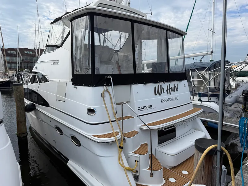 The Image of 2002 Carver 396 Aft Cabin Motor Yacht docked, featuring wood decks and multiple windows. - 0