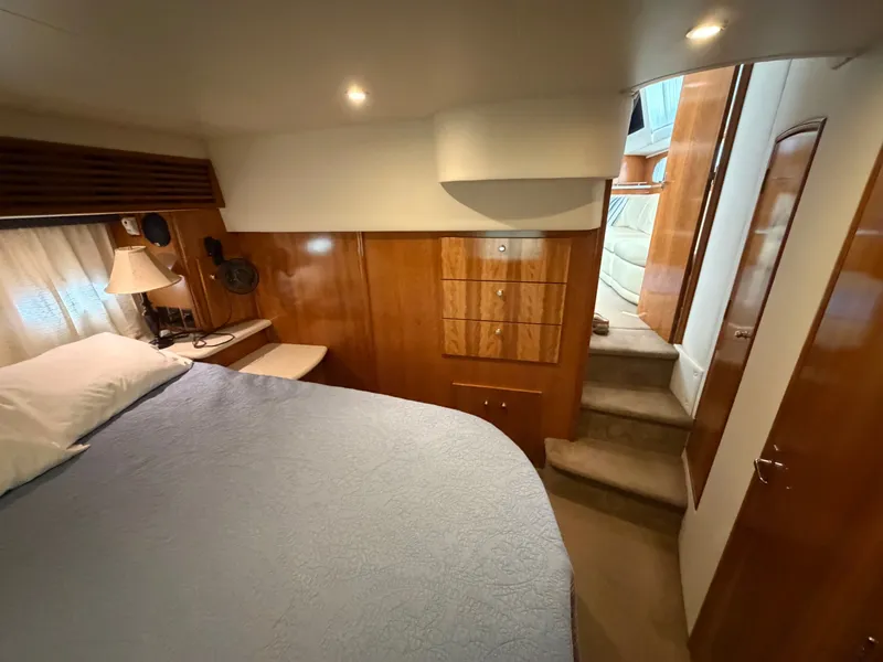 Slide: The Image of Interior of a yacht featuring a cozy bedroom, wooden furnishings, and a bed with a blue cover. - 25