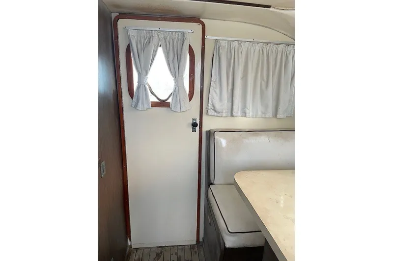 Slide: The Image of Interior of 1979 Bertram 31 Flybridge Cruiser with door, curtains, and seating area. - 6
