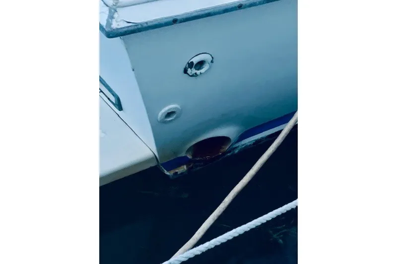 Slide: The Image of 1979 Bertram 31 Flybridge Cruiser hull detail with visible wear and dock lines. - 18