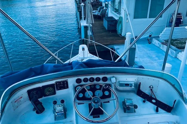 Slide: The Image of 1979 Bertram 31 Flybridge Cruiser cockpit view, docked by waterfront home. - 19