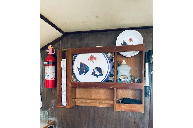 Slide: The Image of Wooden shelf on 1979 Bertram 31 Flybridge Cruiser with plates, fire extinguisher, and cleaning supplies. - 10