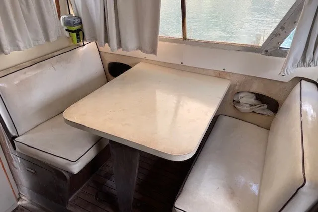 Slide: The Image of 1979 Bertram 31 Flybridge Cruiser interior with white booth seating and table. - 5