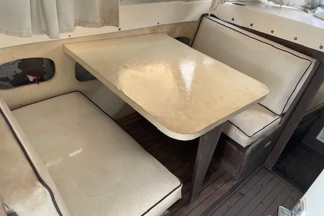 Slide: The Image of 1979 Bertram 31 Flybridge Cruiser interior with vintage dining area and cushioned seating. - 4