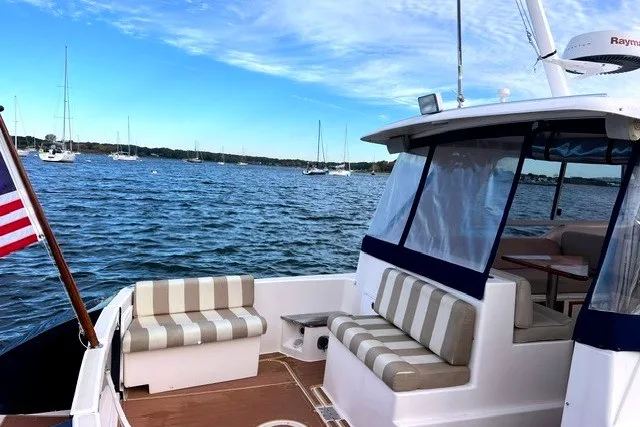 Slide: The Image of 2008 True North 34 boat with striped seating, American flag, and scenic harbor view. - 5