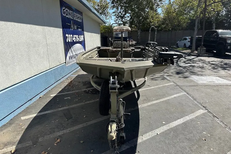 Slide: The Image of 2017 Tracker Grizzly 1860 MVX CC boat parked outside a building on a sunny day. - 17