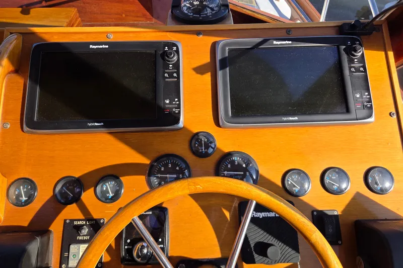 Slide: The Image of Wooden boat dashboard with dual Raymarine displays, gauges, and steering wheel, Able Wolf Class 36, 1998. - 15