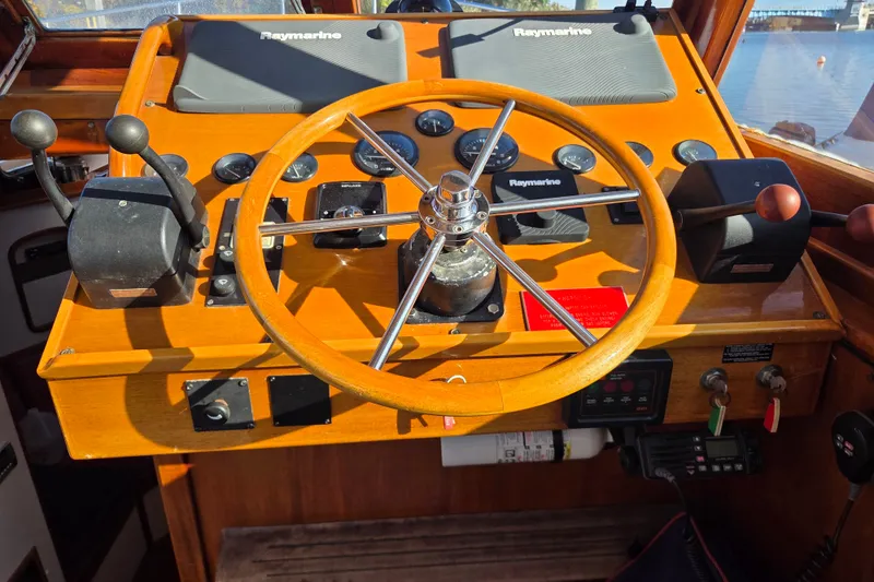 Slide: The Image of Wooden boat helm with Raymarine equipment, featuring dual throttle controls and a classic steering wheel. - 14
