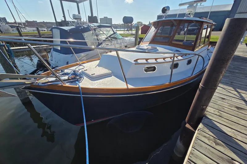 The Image of 1998 Able Wolf Class 36 boat docked at a marina, featuring a classic wooden cabin. - 0